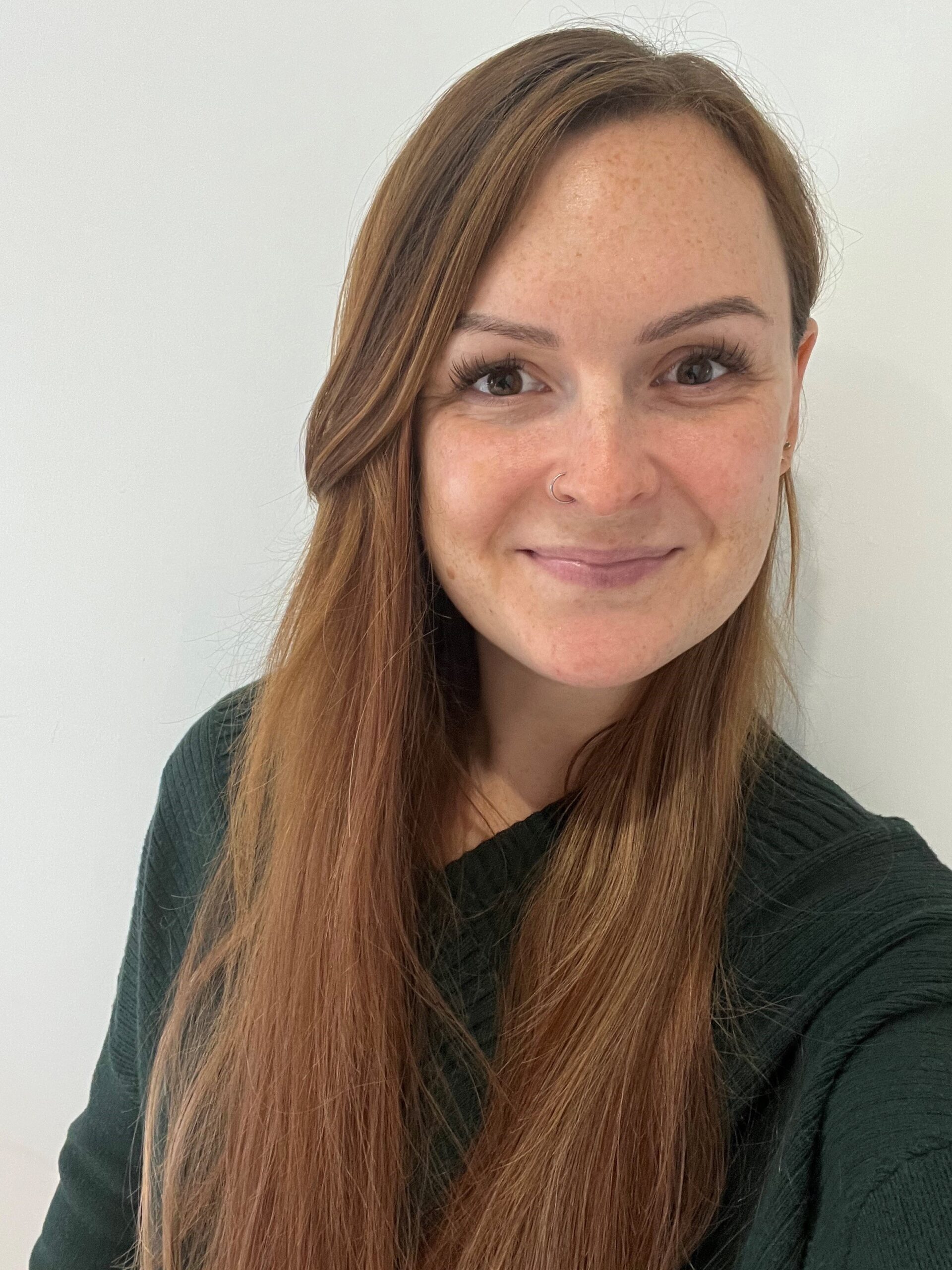 JB pic Trustee Jade Burgess. A smiling woman standing with brown hair